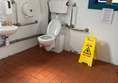 Picture of the toilet with a caution wet floor sign