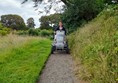Myself on the sturdy National Trust Tramper, riding on a gravel footpath alongside a meadow.