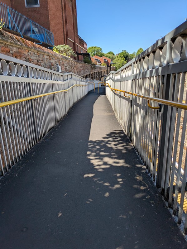 Image of step ramp down to the platforms, there are yellow rails on either side side