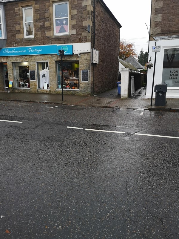 The lane next to Strathcarron Vintage Charity Shop to follow to reach the cafe.