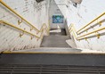 Image of stairs leading to the platforms, there are rails on either side, the edges of the first an last steps are yellow and there are tactile marking at the top