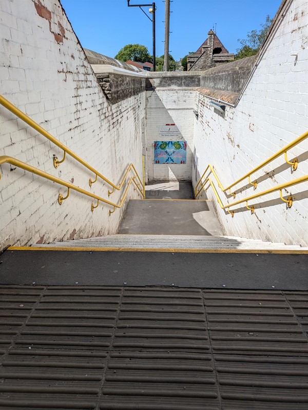 Image of stairs leading to the platforms, there are rails on either side, the edges of the first an last steps are yellow and there are tactile marking at the top
