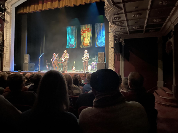 Image of three people on stage playing guitar