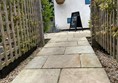 Image of a stone path with a fence and a sign