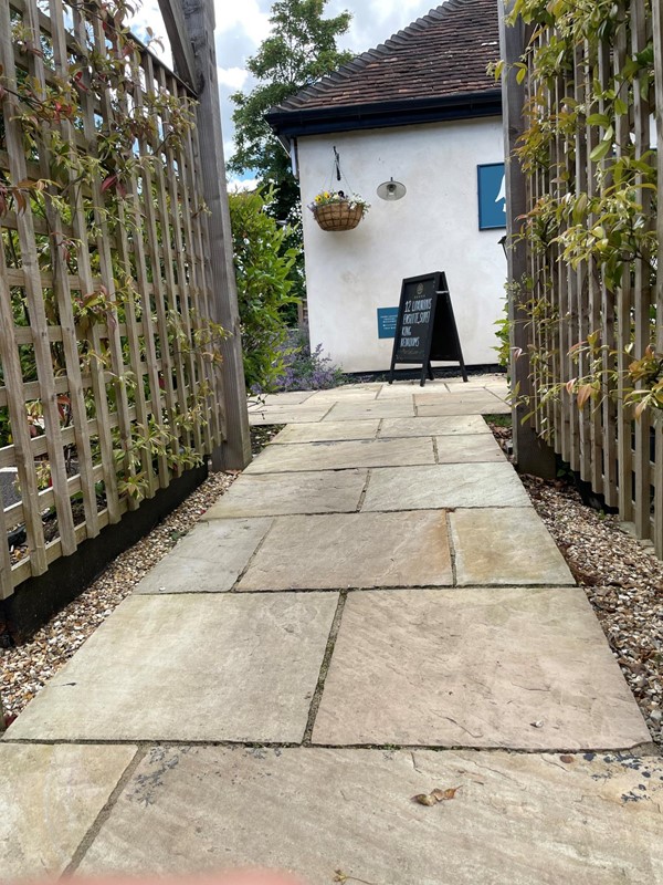 Image of a stone path with a fence and a sign