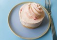 Image of a small pink cupcake on a plate with a fork
