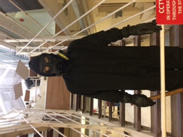 Picture of a mannequin in black clothes and a gas mask