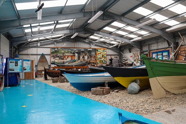 Inside, there is a bright blue path around the edge of the hall. In the middle are several boats.