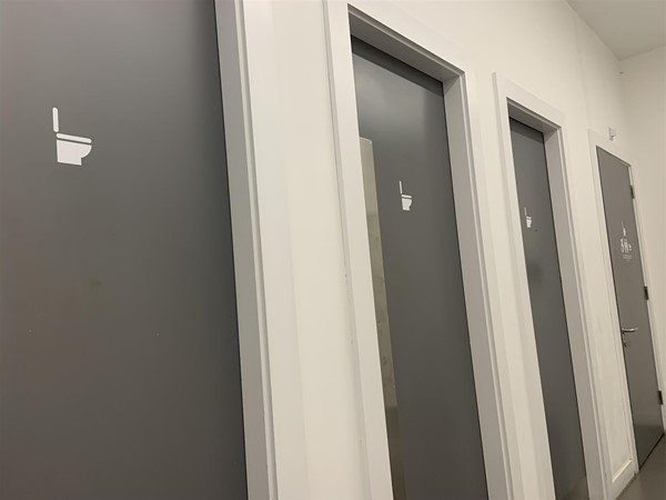 image of four bathroom doors along a corridor
