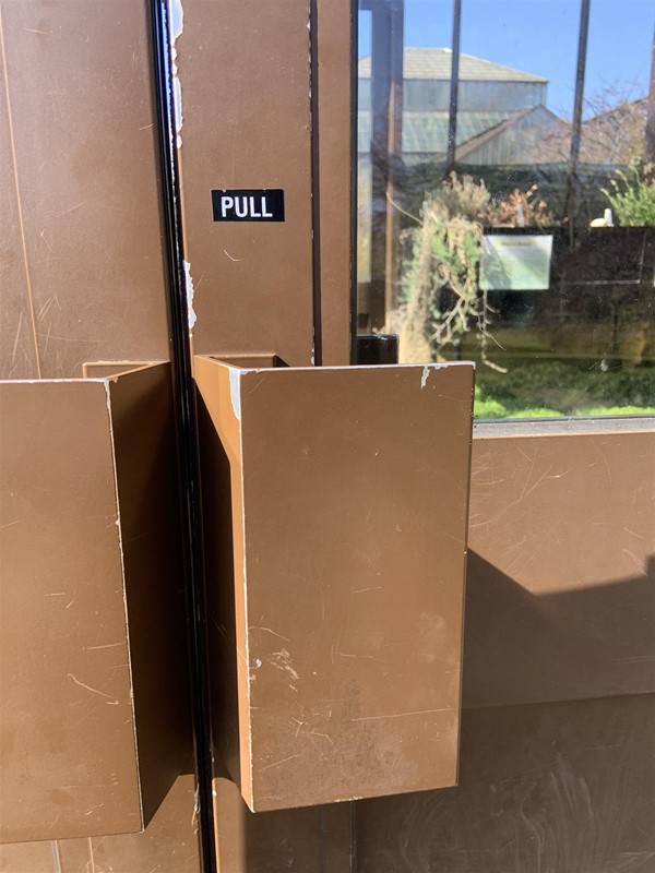 Image of a double door with big rectangular handles and a “pull” sign