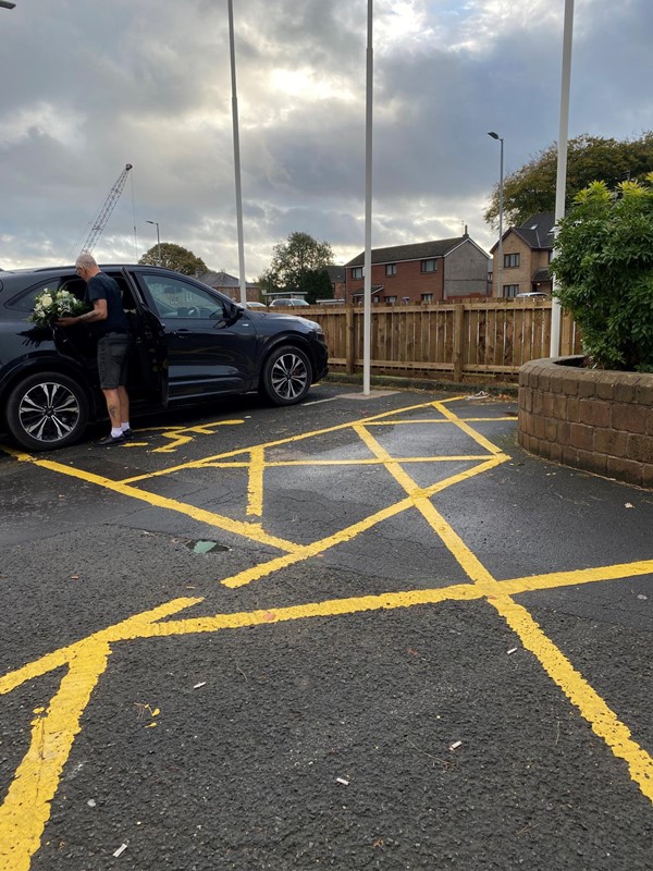Picture of a man with flowers parked in the disabled parking space car park