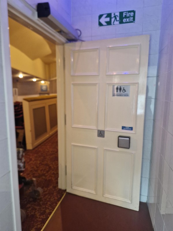 View of the automatic door leading into the accessible toilet. The door has a push button.