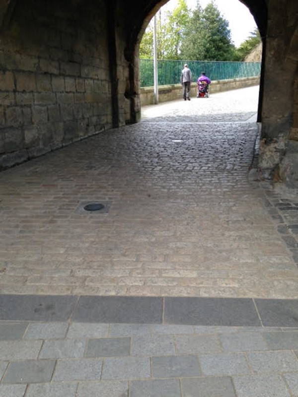 Archway with cobbles but there is level paving to the left through the archway.