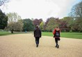 Very wide sweeping gravel path going between beautifully kept lawns with trees around and in the distance.