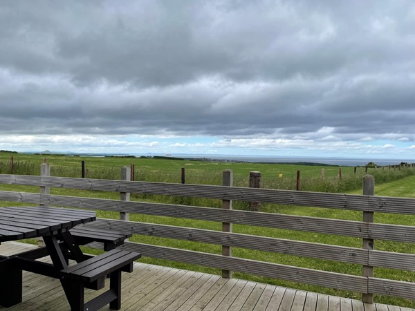 Picture of a picnic bench on decking overlooking a field