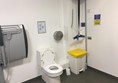 Overhead hoist in corner on charge.
Nappy bin.
Toilet , with pressure switch flush mechanism.
Adult sized, height adjustable bench.