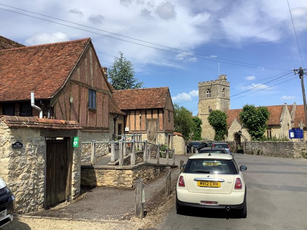 Picture of a car parked in a road with a church in the distance
