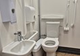 Image of a toilet with a grab rail and a sink
