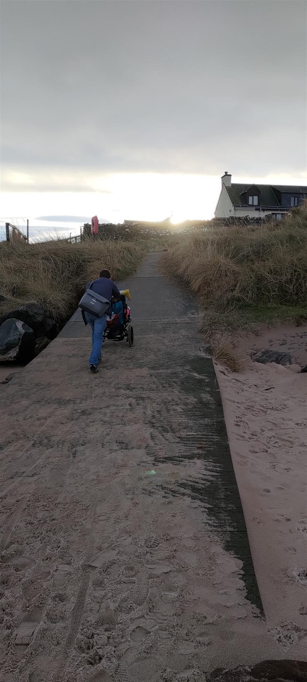 Image of a person wheeling a child up a concrete ramp