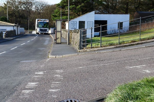 On the other side of the road there is no dropped kerb either. In the main road is a dustbin lorry, which will make it difficult for the wheelchair user to wheel down the road instead of the pavement.