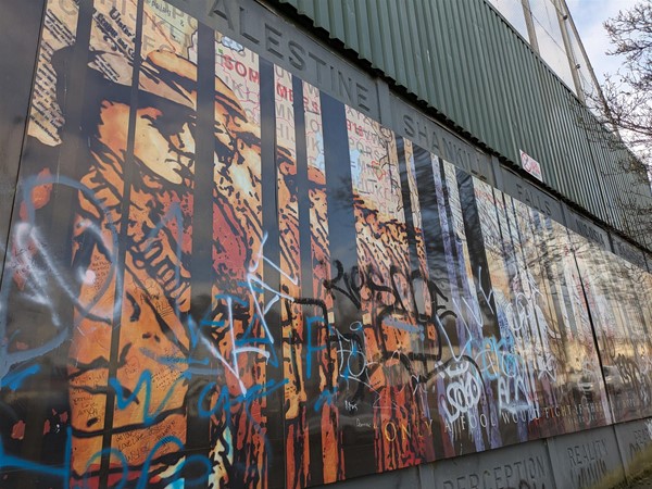 Image of mural showing soldiers, covered in graffiti