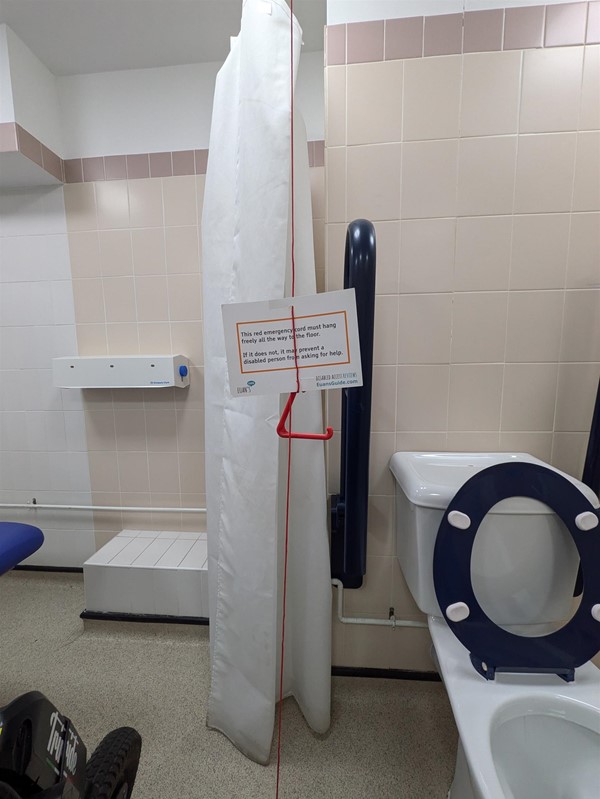 Image of a red cord card hanging from a red cord in the Changing Places toilet