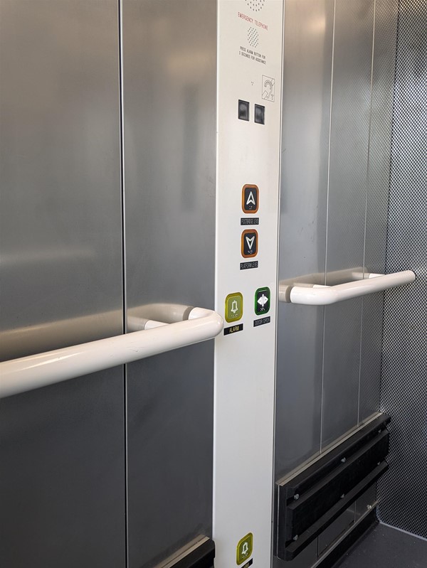 Image of buttons in lift, they have braille markings, there is a lower alarm button close to the floor