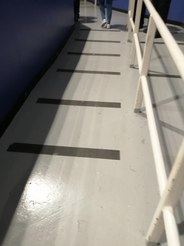 Image of a white railing with black lines on the floor