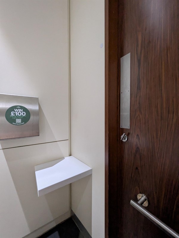 image of inside of door and colostomy shelf in accessible bathroom