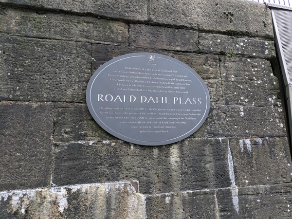 Image of a grey plaque on a brick wall with the writing Roald Dahl Plass