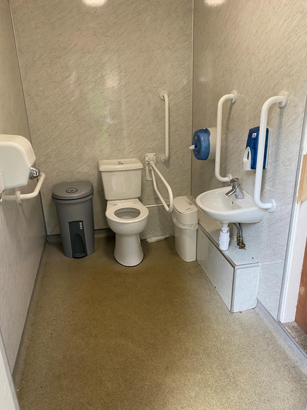 Interior, showing toilet, bars, sink, air hand dryer, and two bins