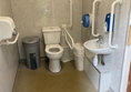 Interior, showing toilet, bars, sink, air hand dryer, and two bins