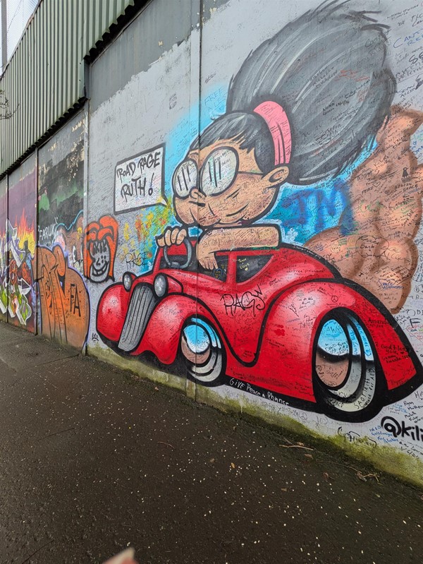 Image of a mural showing an old lady with large glasses driving a red car