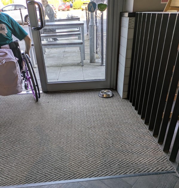 Image of entrance from the inside - there is a dog bowl to the left and a wheelchair user passing through the door