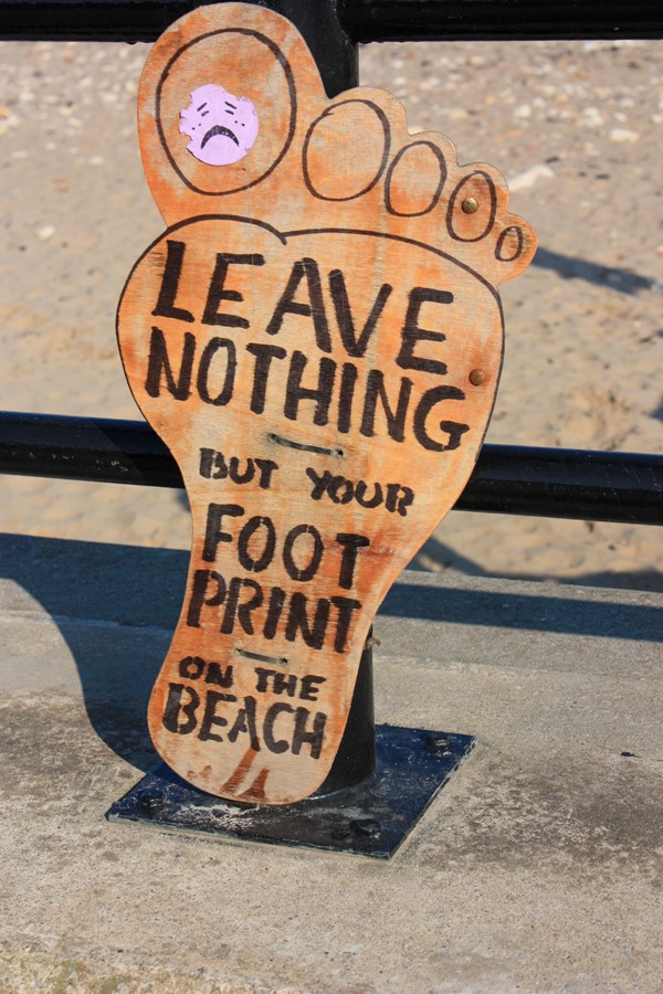 Footprint sign saying, leave nothing but your footprint on the beach.