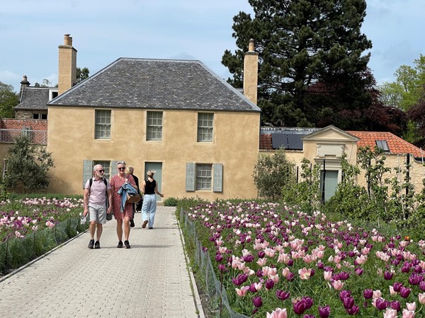 The Gardner's Cottage at the Botanic gardens with two beds of tulips in the front adjacent to the paved walkway