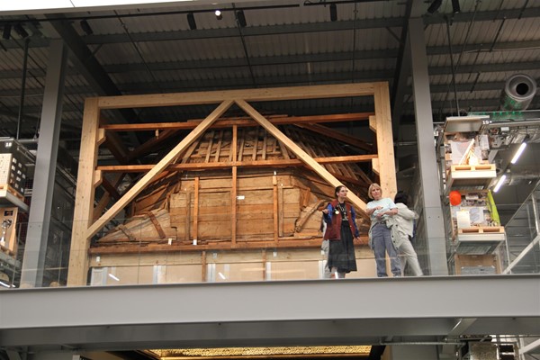 Image of a balcony with people on it, in front of a wooden structure