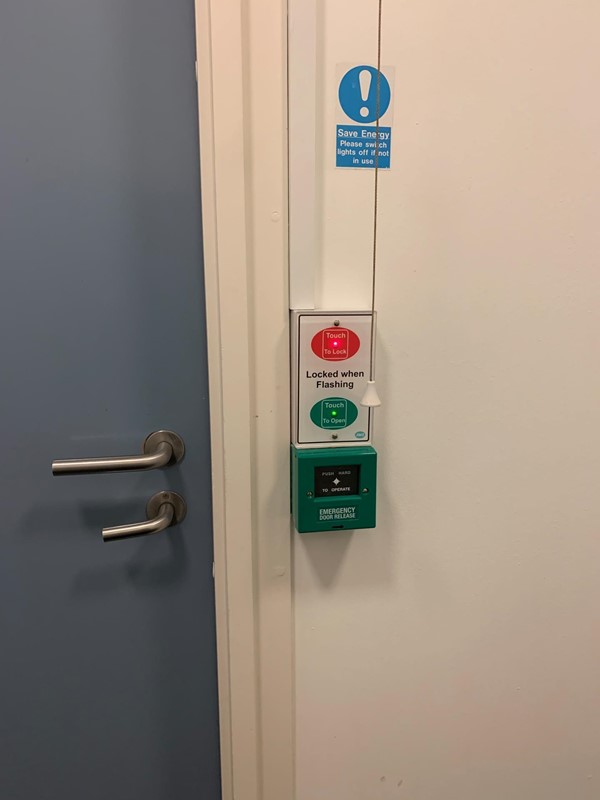 Image of locking mechanism from inside bathroom. The lock is turned on my pushing the red light.