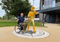 Paul sitting by the yellow jacketed String Man statue at the from of the main entrance to Clynelish Distillery