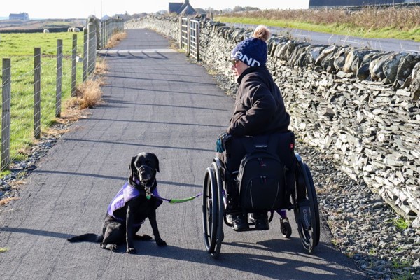 Wheelchair user with assistance dog admiring the views from the path.