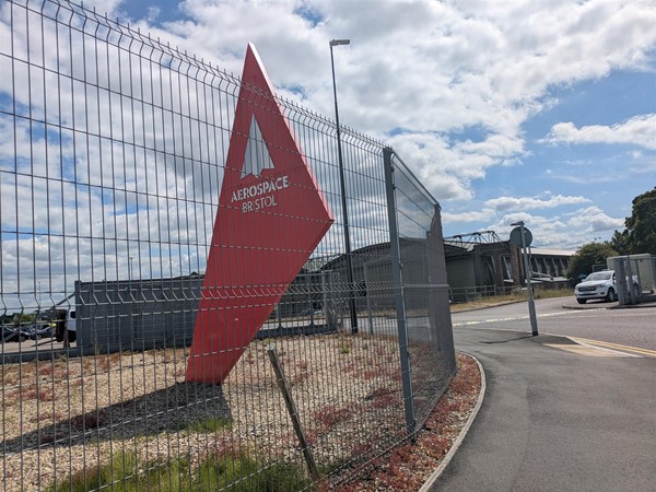 Image of red Aerospace sign near a metal fence.