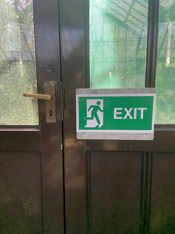 Image of double doors. The left door has a lever handle. The right door has an exit sign on it.