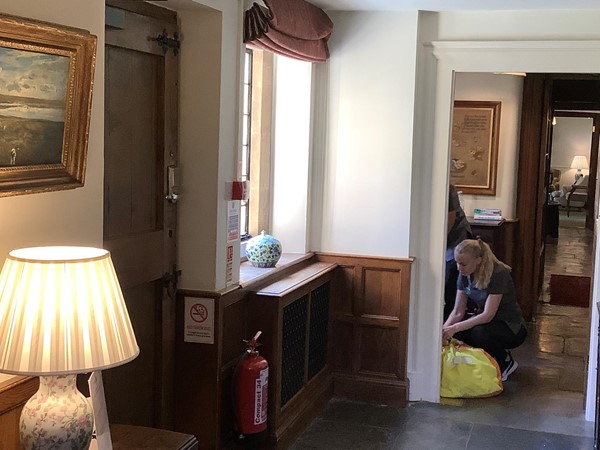 Picture of someone cleaning a corridor with a yellow waste bag