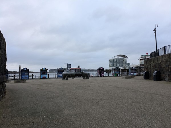Image of the promenade at Cardiff Bay. Several small huts are in the foreground selling tickets to boat tours