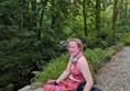 A photo of me enjoying the gardens!

Roz (a white person with pink hair, wearing a pink top and patterned trousers) sits in their manual wheelchair next to a river. Trees are in the background. They are on a gravel path.