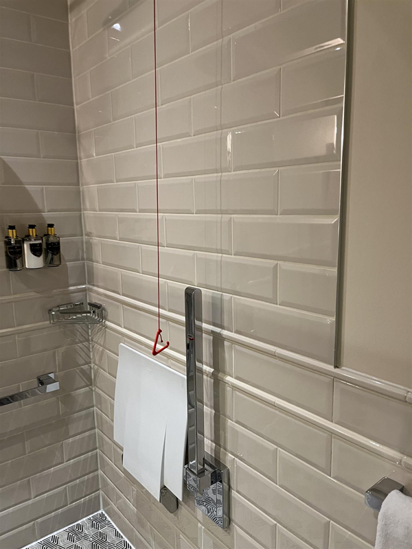Image shows another angle in the wetroom- style in a bathroom in an accessible room at The Grand Hotel, Birmingham. 

There is a red emergency cord hanging from the ceiling but in this picture it does not reach the floor.