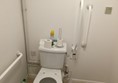 Closer view of the lavatory with grab rails and drop down rail. 