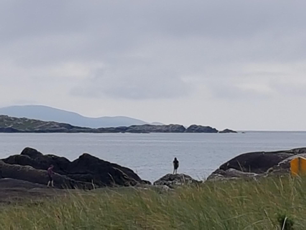 View from the dunes near Derrynane House across the rocky outcrops on the beach to mountains on the peninsula in the distance
