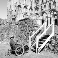 Lady in mountain trike with dog sitting at the bottom of flight of steps.