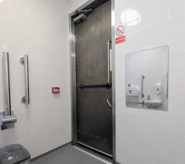 Image of accessible toilet door from the inside with mirror on the wall